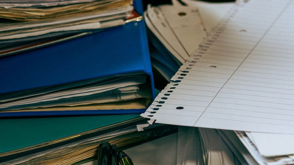 Collected preference sheets and tally documents piled on a desk — paper-based meeting scheduling