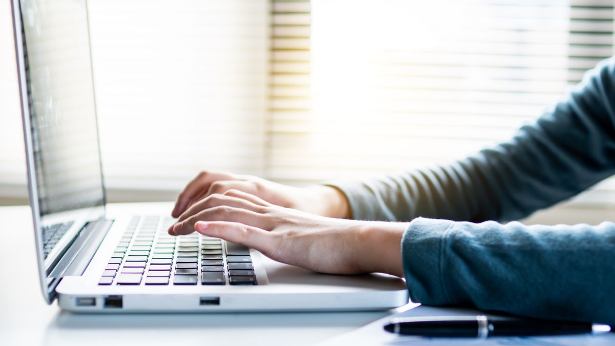 Hands typing a booking confirmation email on a laptop