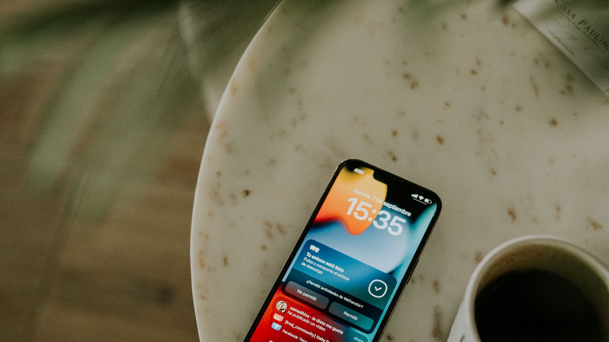 A smartphone showing notifications on a table beside a coffee cup