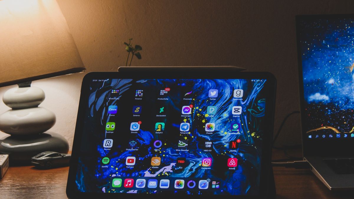 夜のデスクでノートパソコンとタブレットを使う作業風景
