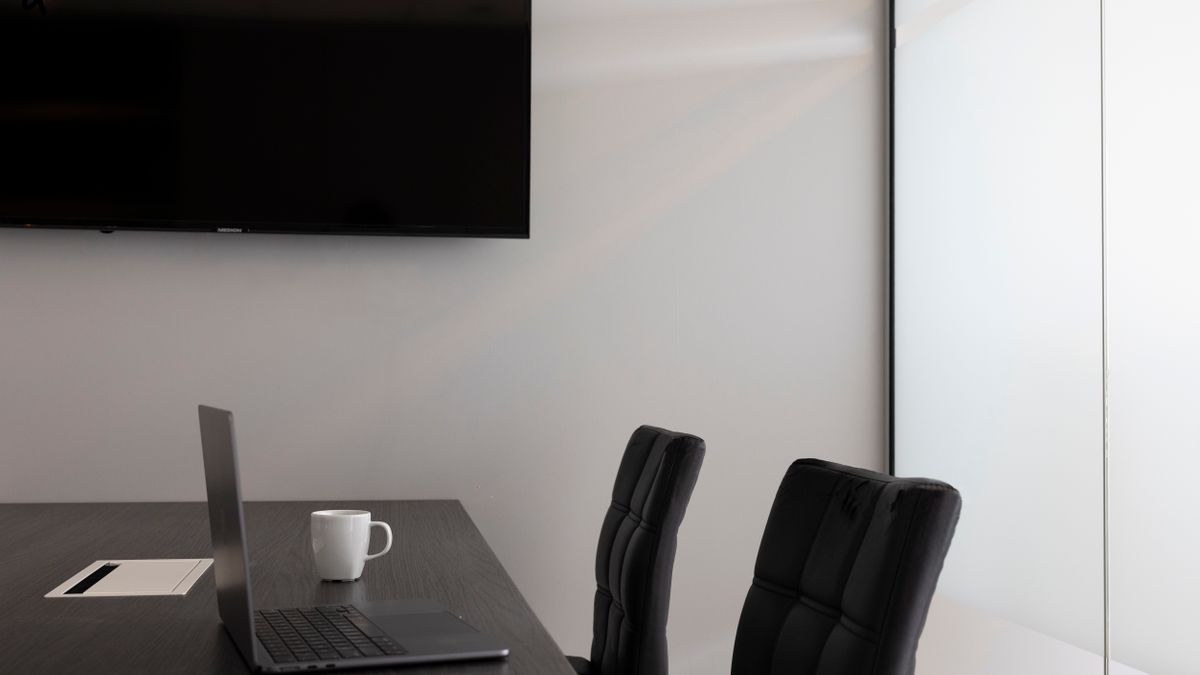 A laptop in an empty meeting room, ready to schedule the next meeting