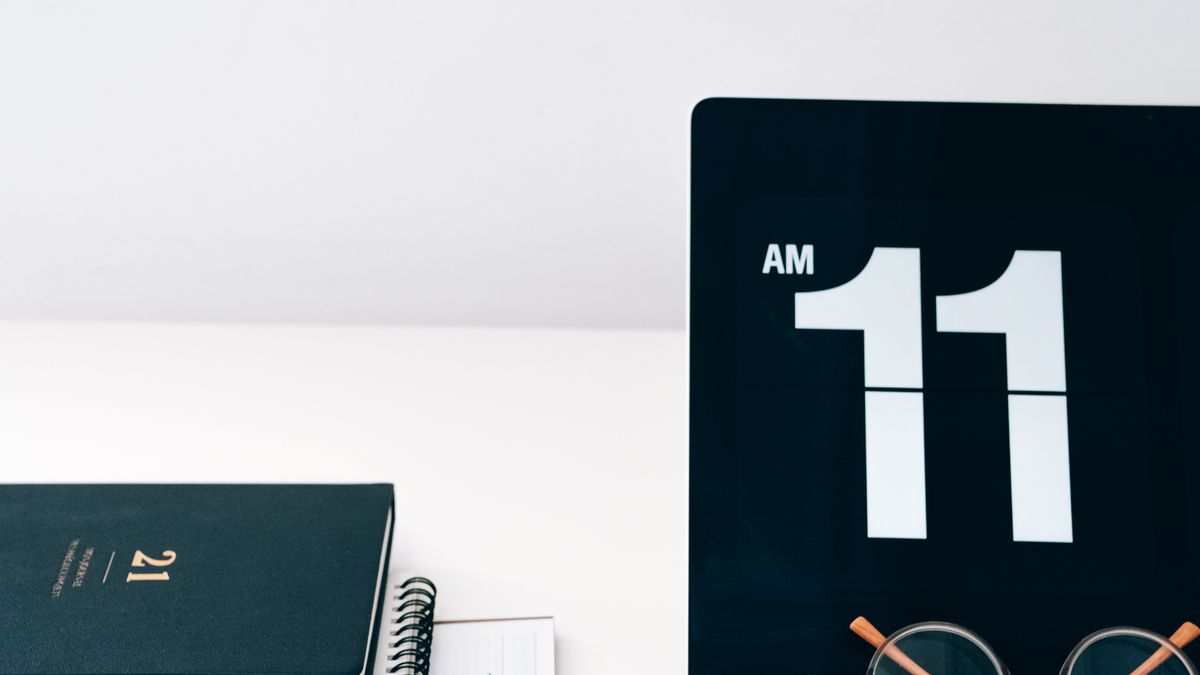 A planner and clock on a desk, representing booking slots and calendar management