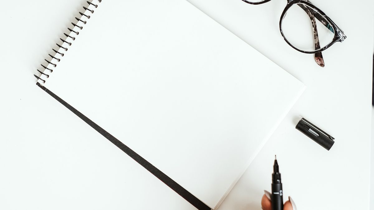 A blank notebook and glasses on a white desk, for reviewing MOSH's pricing