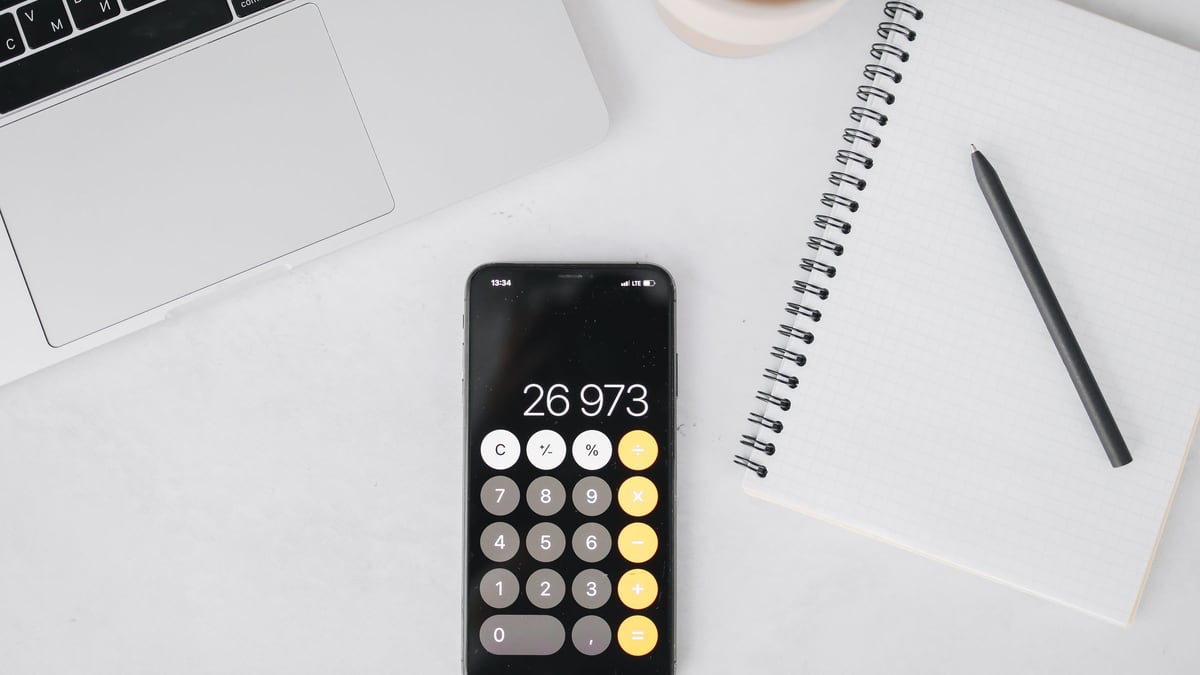 ノートとスマートフォンの電卓。手取りの分岐点を計算する
