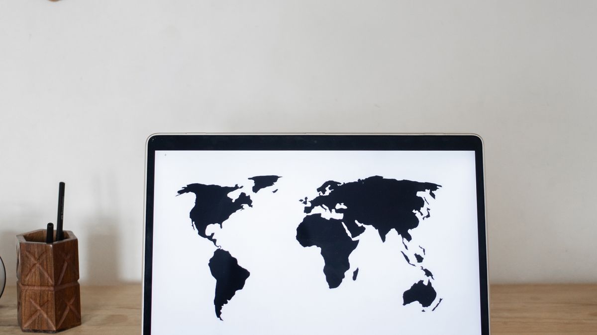 世界地図を映したノートパソコン。海外の生徒から得たドルの残高を円で受け取る